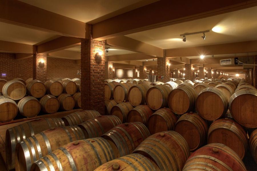 wine wood barrels on top of each other at 'Domaine Skouras' stone cellar